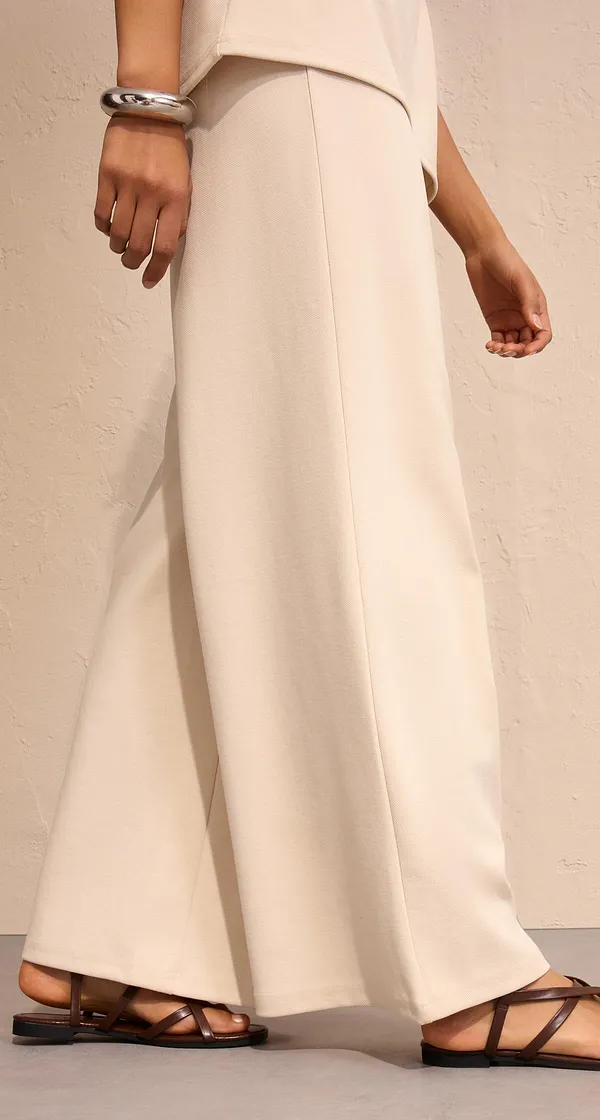 Pantalon large élégant couleur crème, associé à des sandales plates.