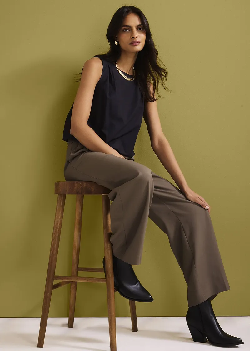 Top sans manches bleu foncé, pantalon large marron et bottines noires. Un look décontracté chic.