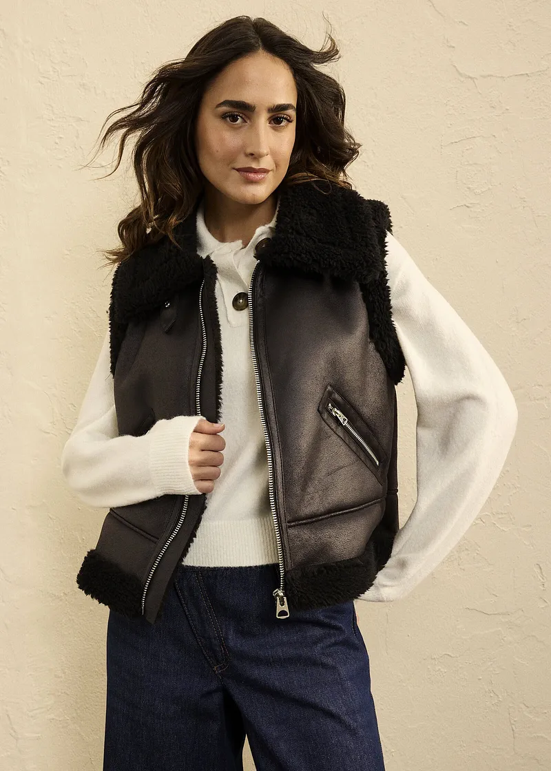 Veste sans manches enduite avec col douillet, pull en maille blanc et jean : une tenue d'automne décontractée pour les fraîches journées.