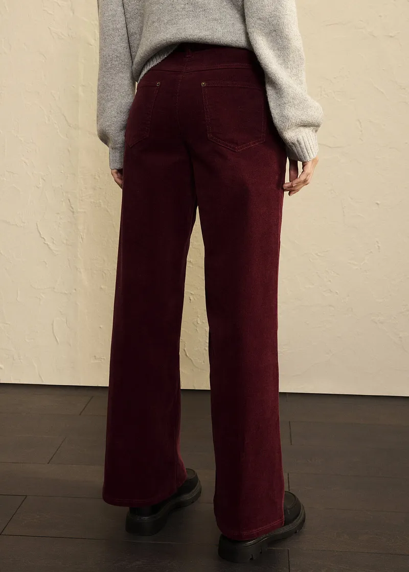 Tenue élégante composée d'un pull gris et d'un pantalon en velours rouge bordeaux.