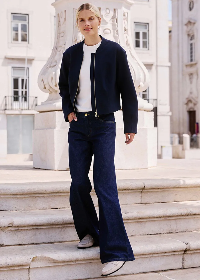 Look élégant avec veste foncée, haut blanc et jean évasé.