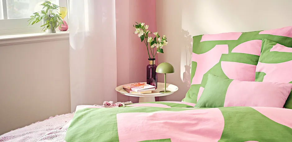 Une parure de lit fraiche en rose et vert pour une ambiance estivale dans une chambre claire.