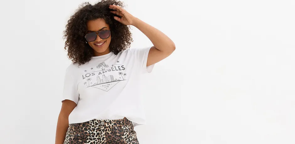 T-shirt blanc décontracté avec imprimé et jupe à motif léopard. Lunettes de soleil en accessoire.