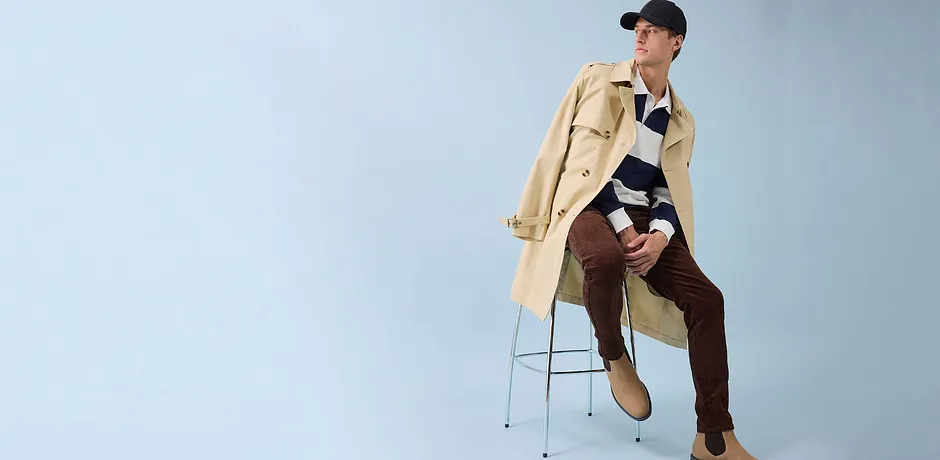 Trench-coat élégant, pantalon marron et casquette noire - un look moderne pour le quotidien.