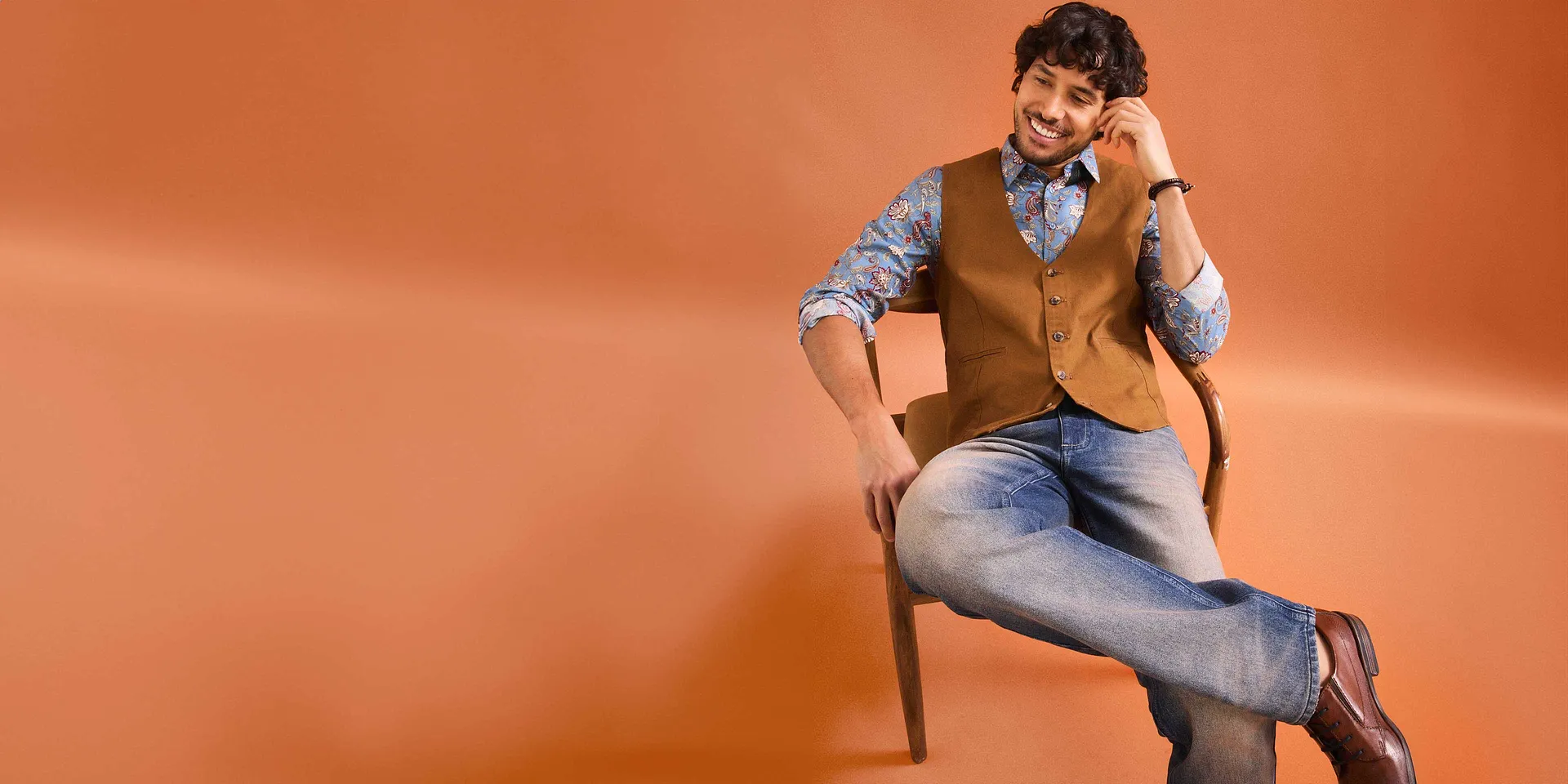Tenue stylée composée d'un jean, d'une chemise à motifs et d'un gilet marron sans manches.