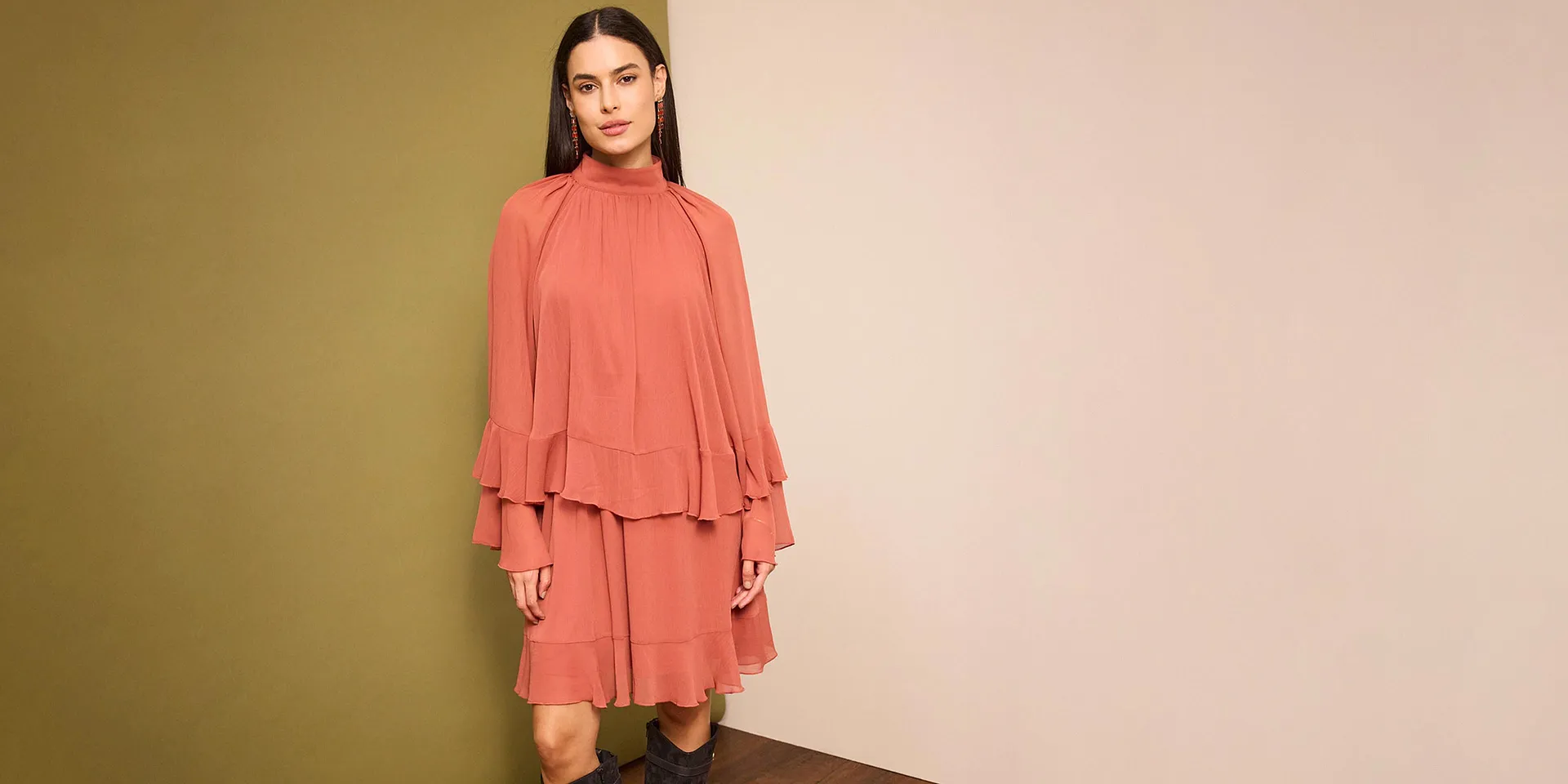 Une robe couleur saumon avec volants et manches amples soulignant la silhouette féminine. 