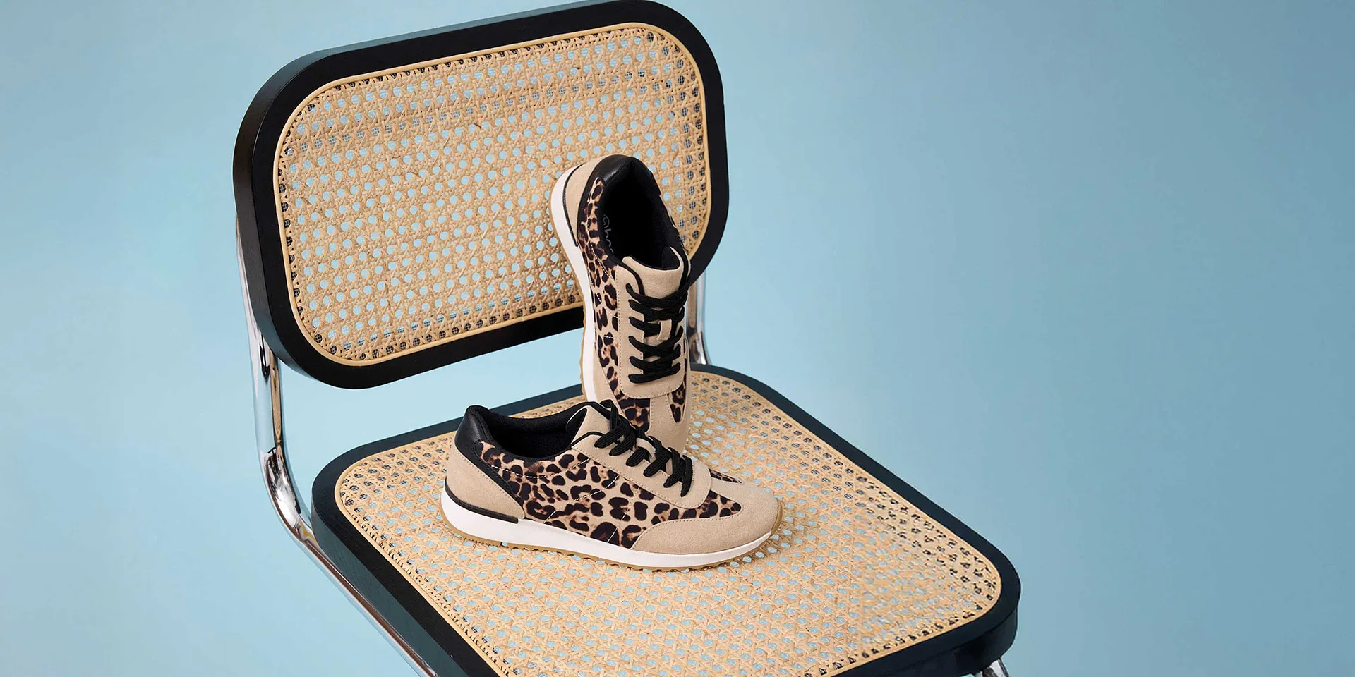 Sneakers léopard stylées sur une chaise tressée.