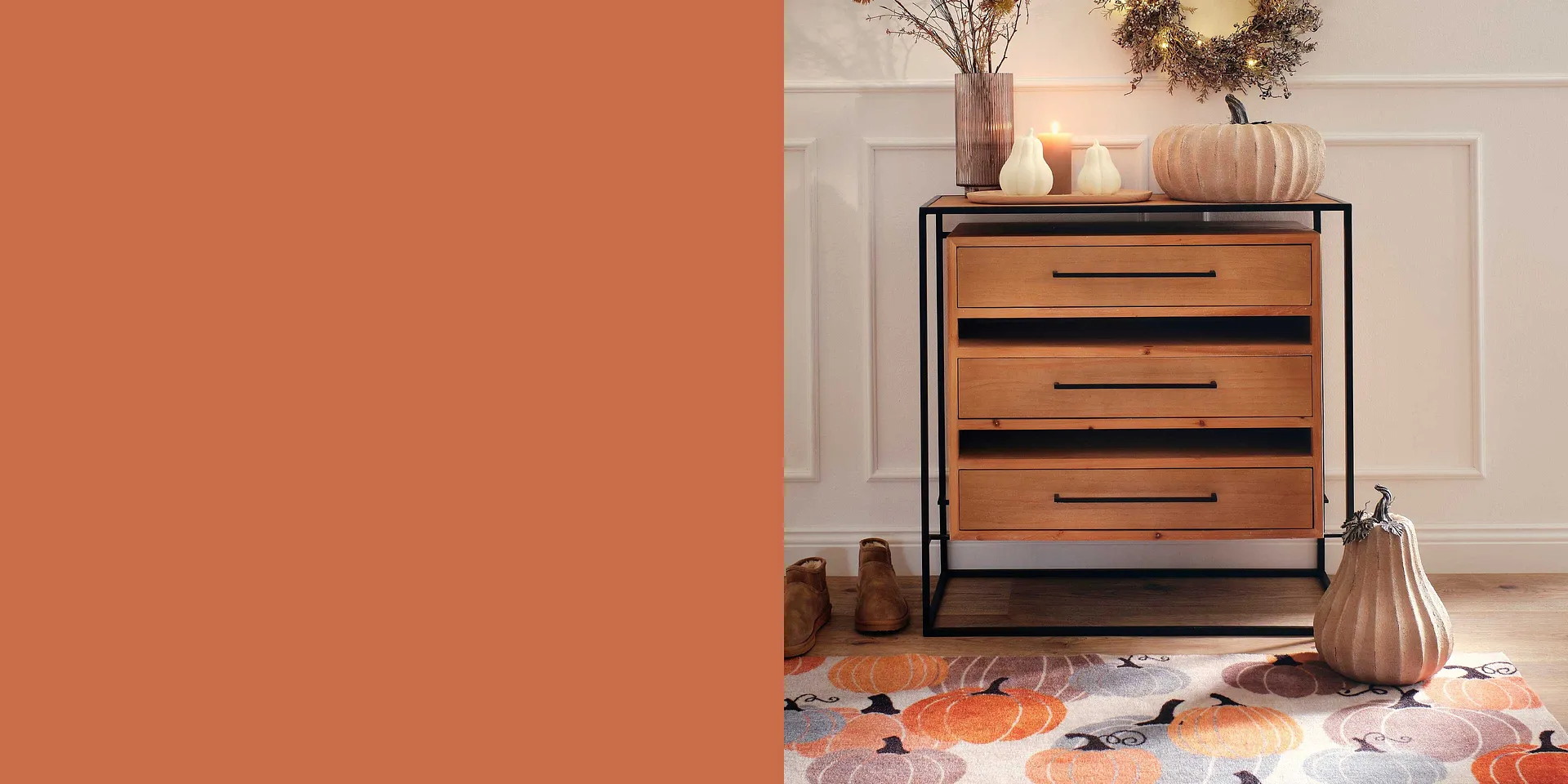 Commode en bois avec poignées noires, entourée d'objets de décoration d'automne dans des tons chauds et terreux. 