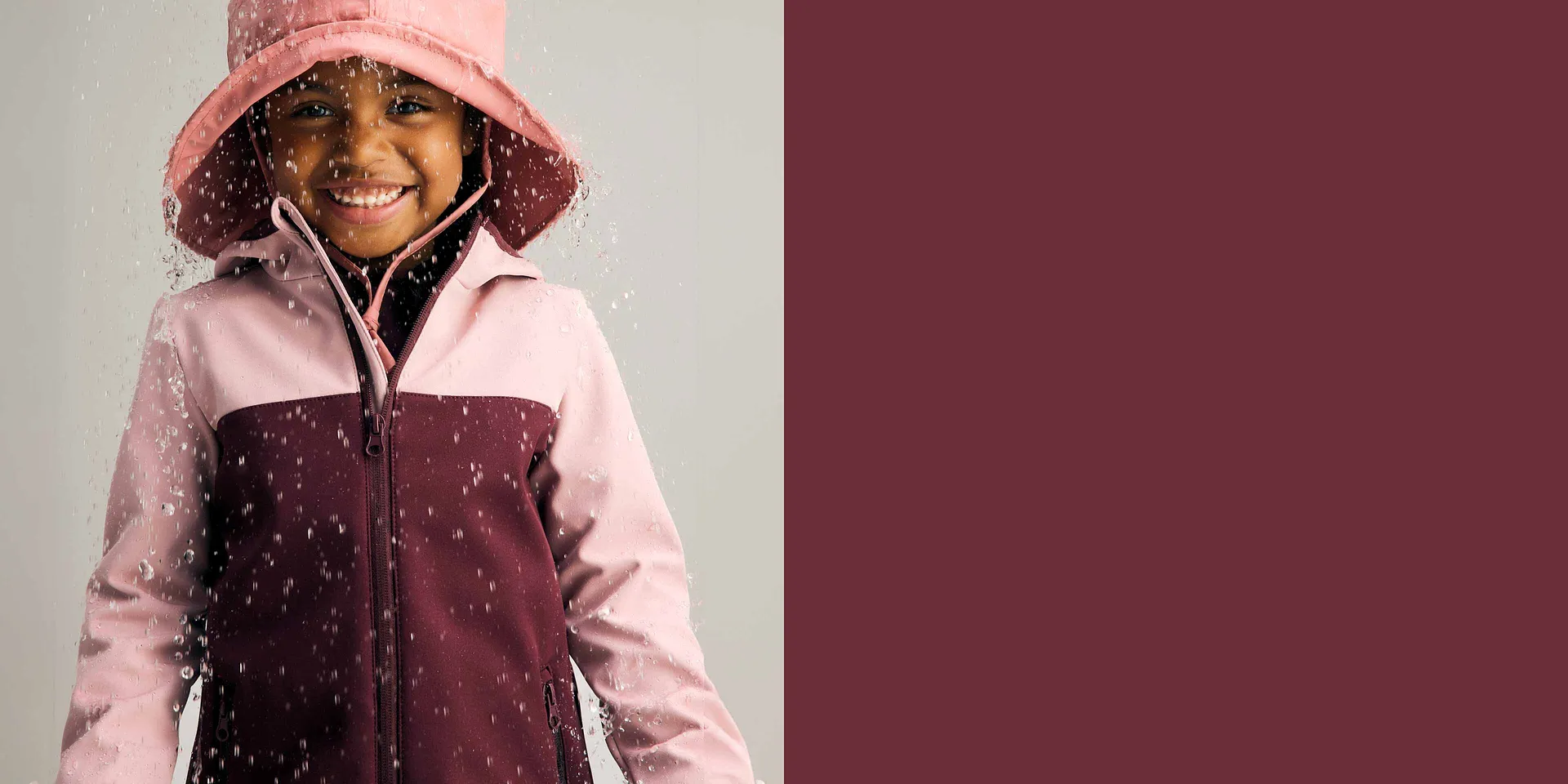 Veste imperméable en rose et bordeaux, chapeau de pluie assorti.