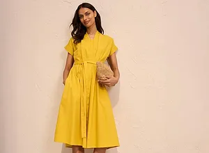Robe-chemise jaune estivale ceinturée, longueur genou et à manches courtes. Complétez avec des sandales noires et un sac à main en paille.