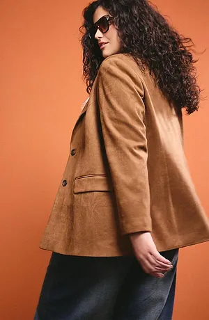 Veste marron camel élégante avec gros boutons, associée à une jupe foncée et lunettes de soleil mode.