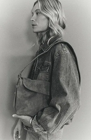 Une veste en jean classique avec rivets, associée à un sac à main sobre pour un look décontracté.