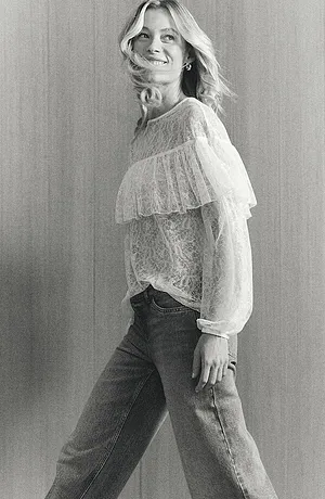 Blouse blanche romantique en dentelle avec volant, associée à un jean classique pour un look décontracté chic.