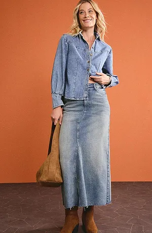 Total look jean, de la tête aux pieds : chemise en jean et jupe longue en jean associées à des bottes marron.
