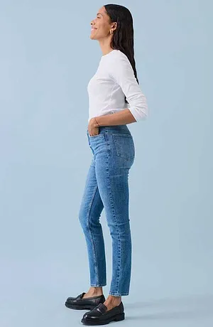 Look décontracté avec T-shirt blanc à manches longues, jean bleu près du corps et chaussures noires.