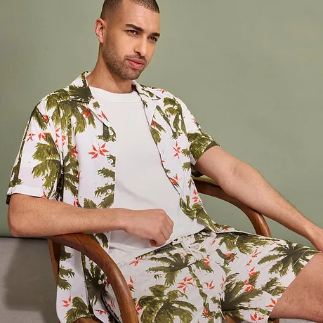 Chemise tropicale et short à motif palmiers, T-shirt blanc basique en dessous.