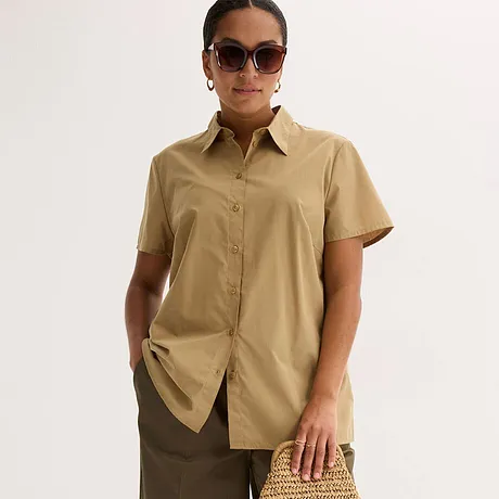 Chemisier beige élégant à manches courtes avec col, associé à une jupe marron et complété de lunettes de soleil stylées.