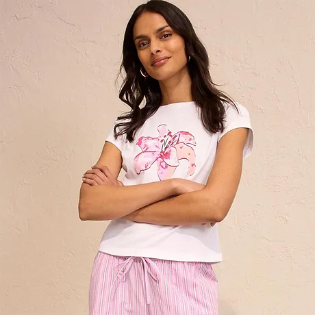 T-shirt blanc à fleur rose, complété d'un pantalon de pyjama rayé. Un look confortable et décontracté.