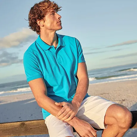 Look décontracté pour la plage : polo turquoise et short clair.