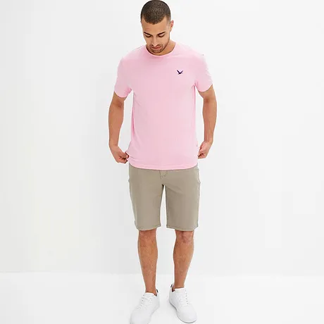 Un T-shirt rose avec un petit logo et un short beige créent une tenue estivale.