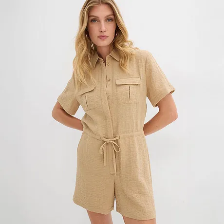 Combinaison beige à manches courtes avec col chemisier, ceinture et poches poitrine.