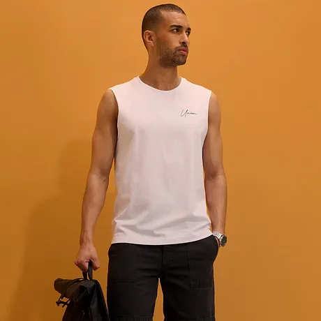 Débardeur blanc, short foncé, sneakers blanches et sac à dos noir.