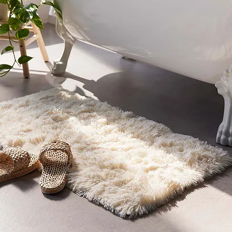 Tapis de salle de bain douillet devant une baignoire.