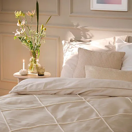 Une parure de lit à motif géométrique décore le lit. Des coussins blancs composent une atmosphère chaleureuse.