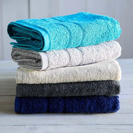 Une pile de serviettes douces de différents coloris : turquoise, blanc, beige, gris foncé et bleu marine.