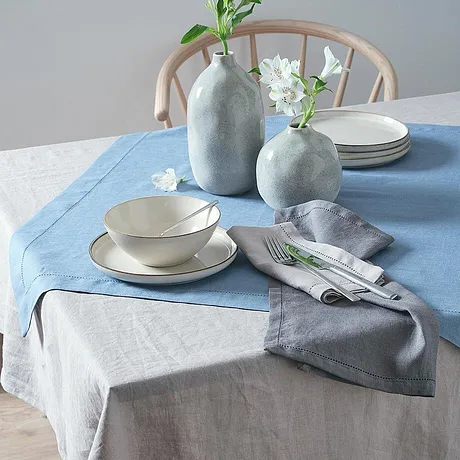 Des nappes bleues et grises décorent la table, des vases clairs et épurés complètent l'ambiance.