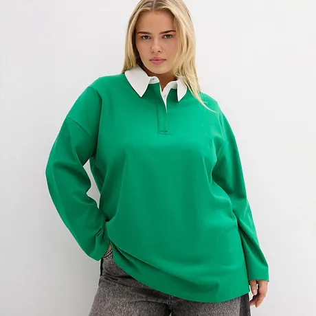 Polo vert émeraude à col blanc, associé à un pantalon gris.