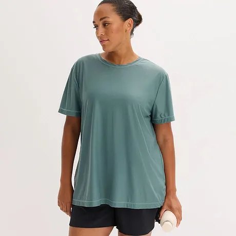 T-shirt vert sauge fonctionnel de coupe ample avec encolure ronde et manches courtes, associé à un short foncé.