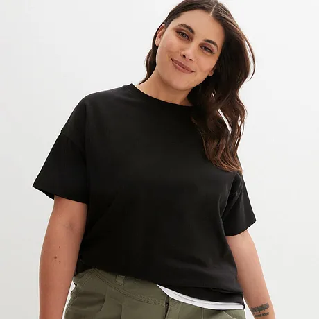 Un T-shirt noir basique à col rond et manches courtes, associé à un pantalon vert olive.