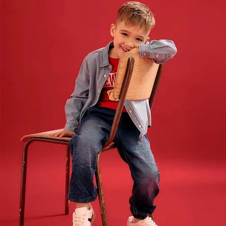 Look cool avec veste grise, T-shirt rouge, jean et baskets blanches.