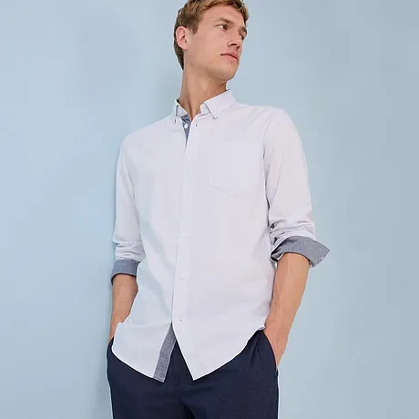Chemise blanche avec col et manches retroussées.