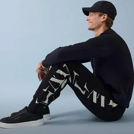 Pantalon sweat, pull foncé et baskets pour un look sportif mode.