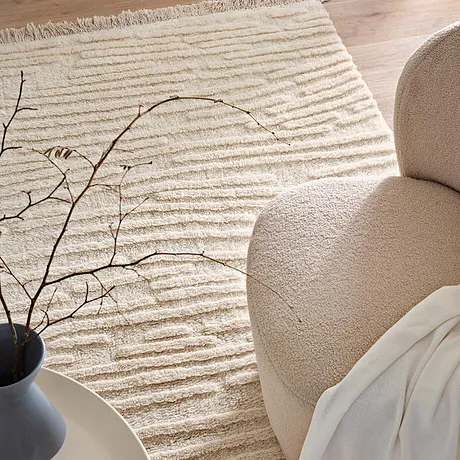 Salon à l'ambiance cocooning avec tapis douillet, fauteuil moelleux et plaid tout doux pour des heures de détente. 