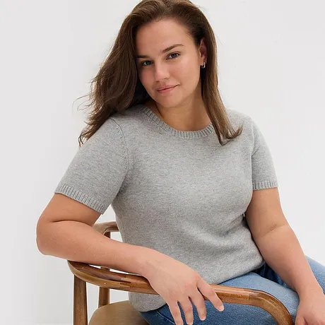Pull gris à manches courtes, associé à un jean bleu.
