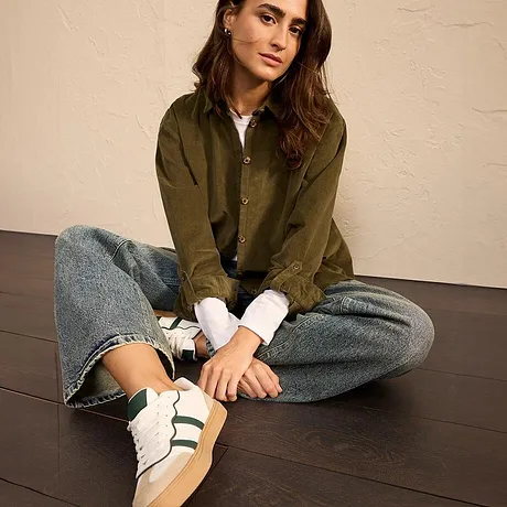Veste vert olive, jean et sneakers blanches avec rayures vertes.