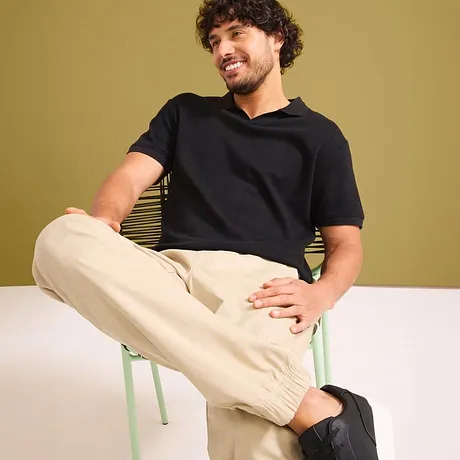 T-shirt noir et pantalon clair en coton.
