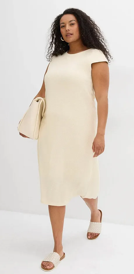 Robe simple de couleur crème à manches courtes, accompagnée de sandales claires et d'un sac à main assorti.