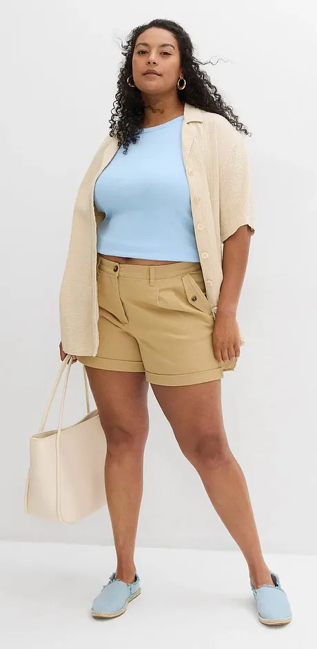 Tenue estivale avec un top bleu clair, un cardigan beige, un short kaki et des chaussures assorties.