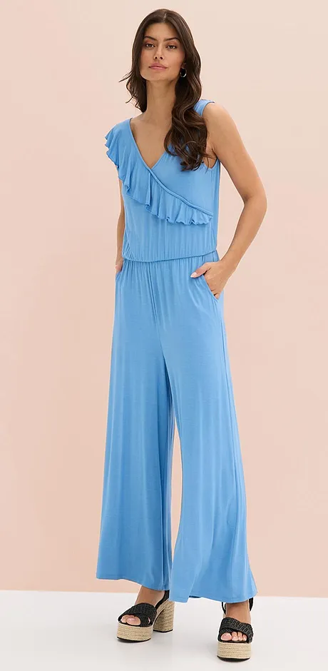 Combinaison bleu clair à ruchés, décolleté en V et jambes larges. Une tenue estivale légère et aérienne pour les chaudes journées.
