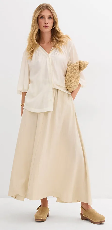 Tenue légère et estivale couleur crème avec un chemisier ample et une jupe longue.