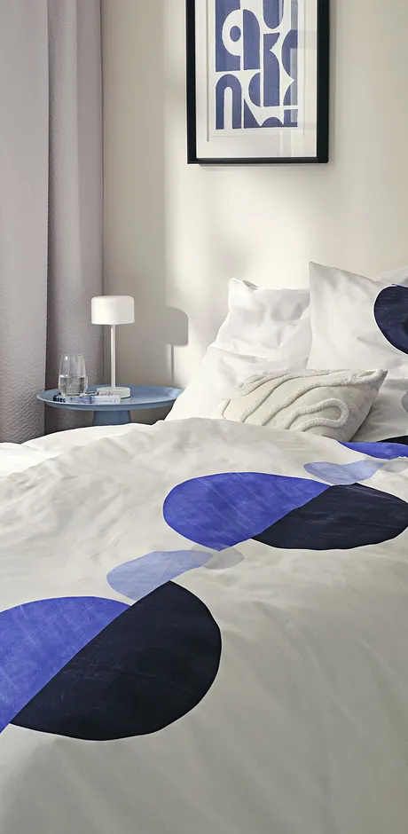 Parure de lit moderne avec motif géométrique en bleu et noir sur un fond blanc.