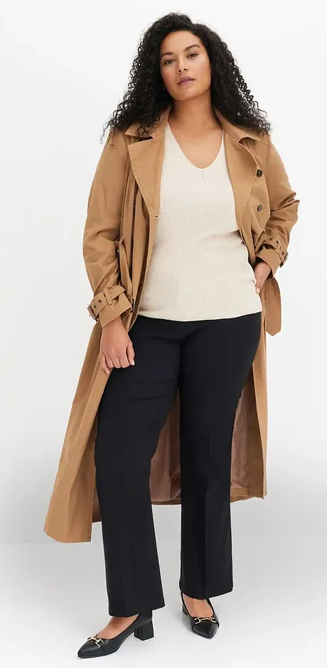Trench-coat beige classique sur un top blanc et un pantalon foncé.