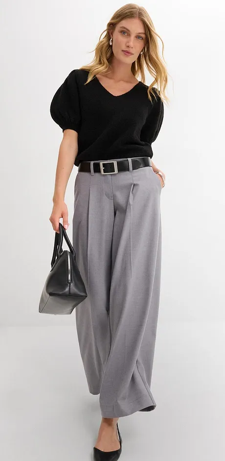 Look élégant avec une blouse noire, un pantalon large gris et une ceinture chic.