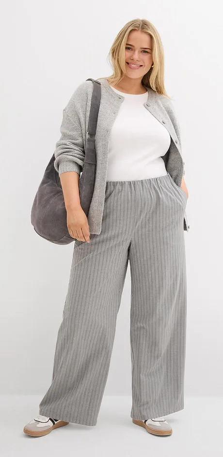 Gilet en maille gris avec top blanc et pantalon rayé gris.
