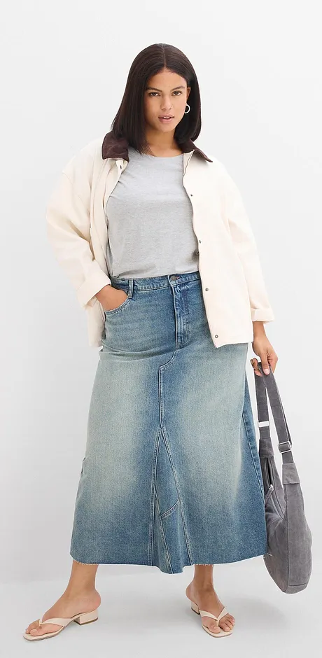 Veste blanche douillette, top gris, jupe longue en jean et sandales confortables.