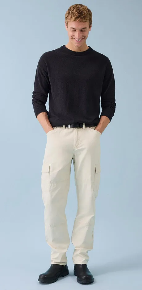 Look classique : pull foncé associé à un pantalon cargo de couleur claire.
